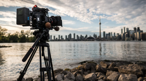 20 avantages et inconvénients pour la production vidéo intérieure et extérieure 2 Une image qui montre une caméra dehors, devant la ville et le lac, prise par une vidéaste chez Fullframe Creative.