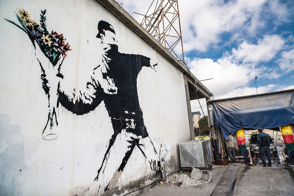 a photograph by Valerio Berdini showing Banksy's flower thrower next to some people at a car wash