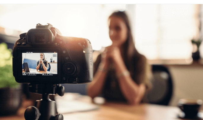 Une image qui montre une femme qui fait un interview sur vidéo.