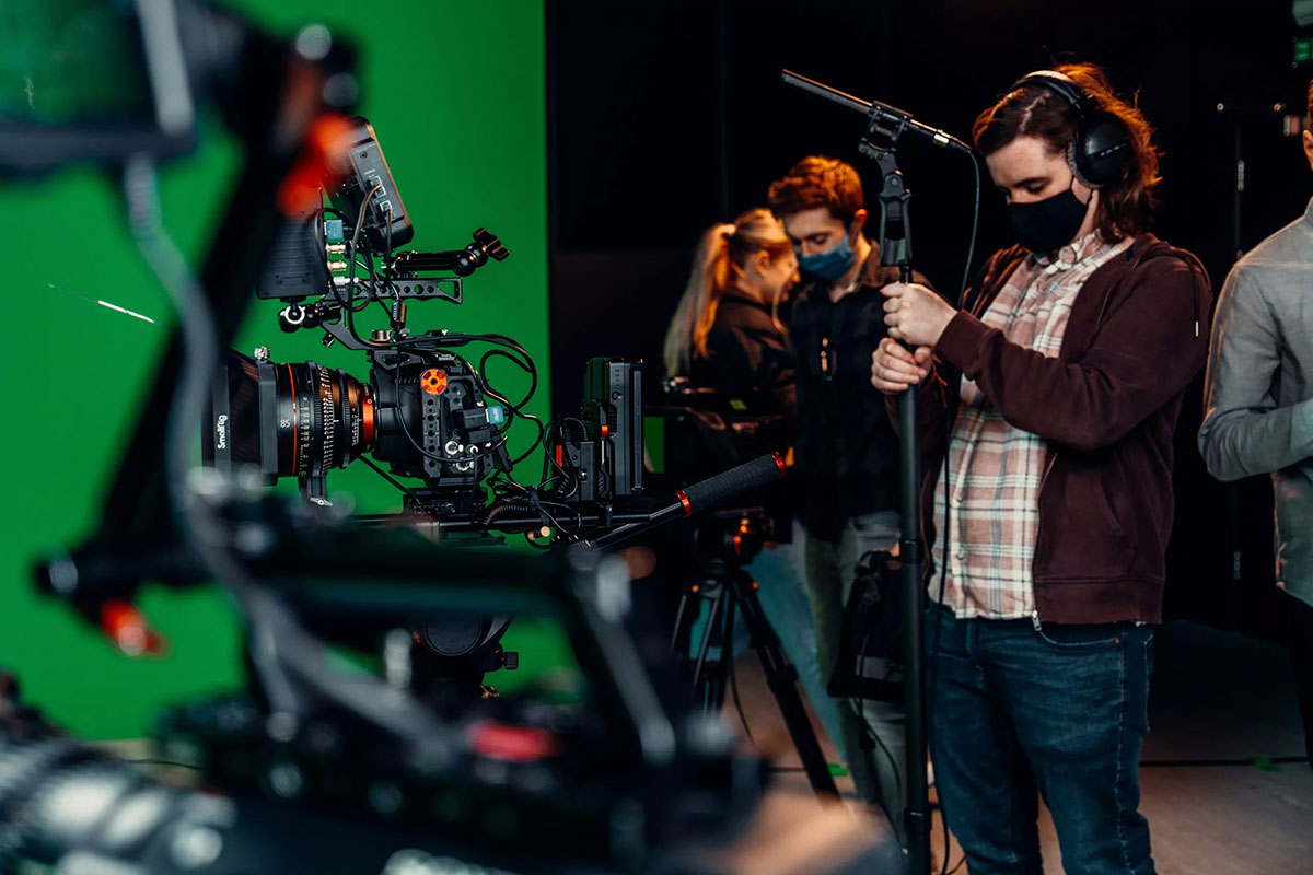 A video production crew working in a green screen studio, image by Ben Collins on unsplash