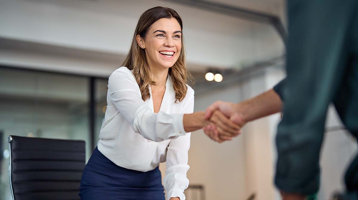 Corporate photography of an executive woman shaking hands in an office by the Fullframe Creative Agency.