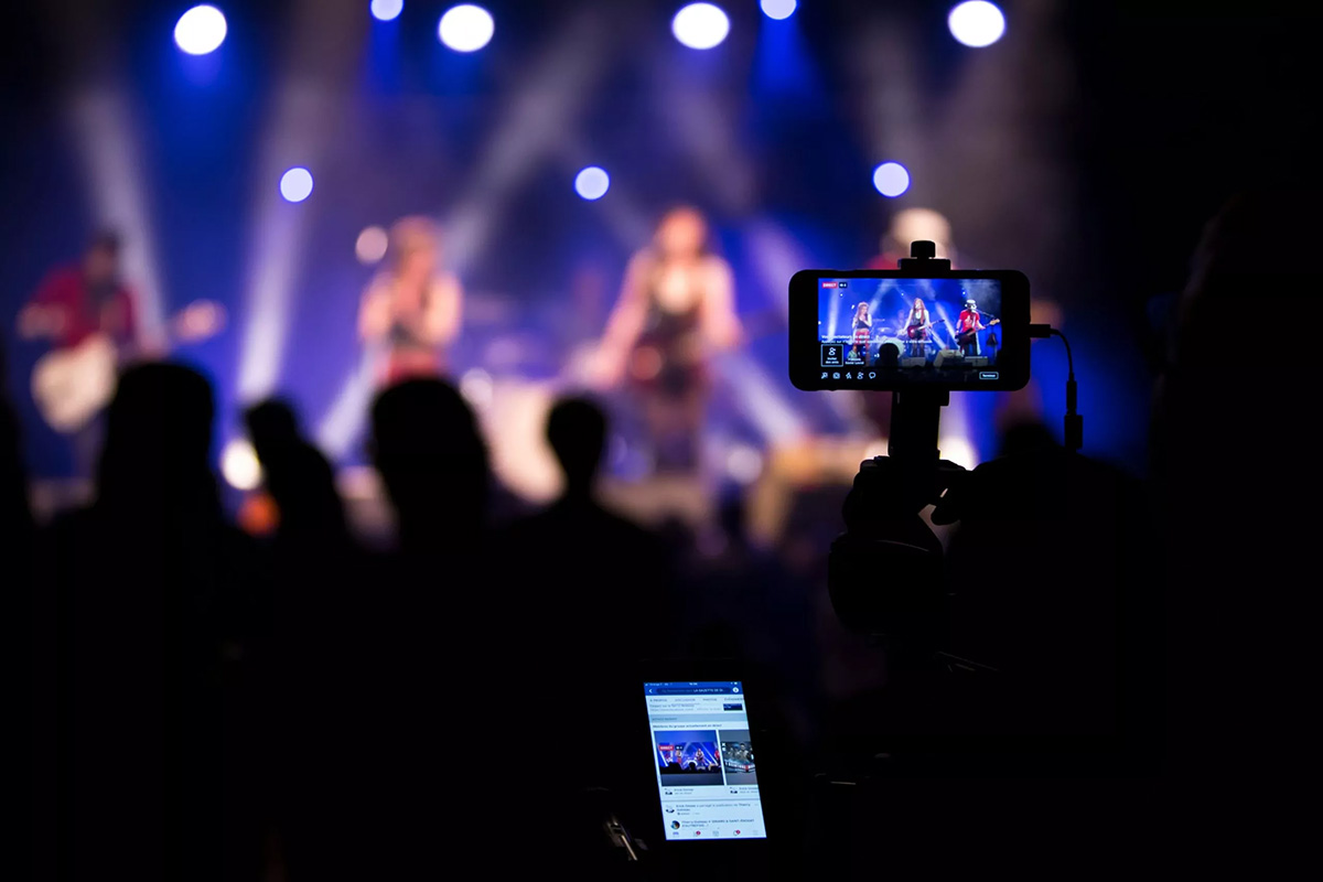 image of someone livestreaming and recording a concert, image from nicolas lb on unsplash