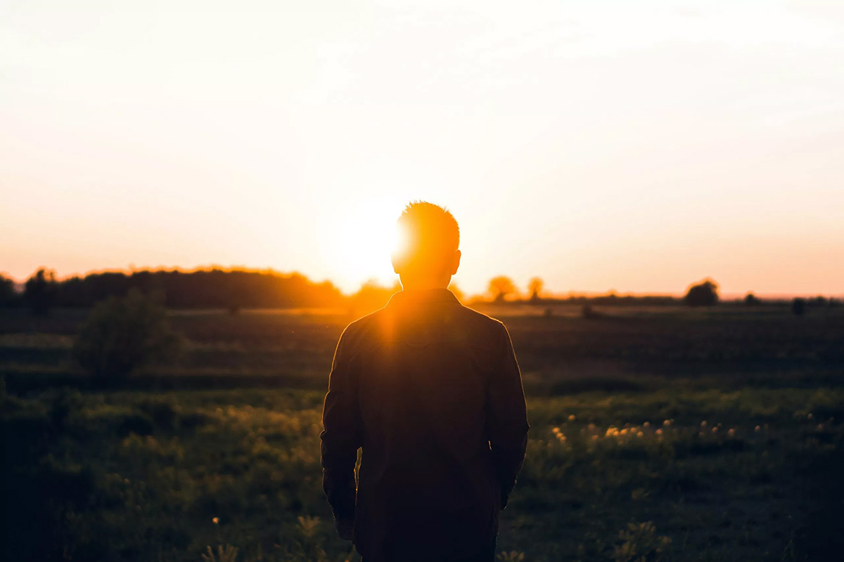 a man standing in a field with the sun shining, warren wukitusjrgy on unsplash